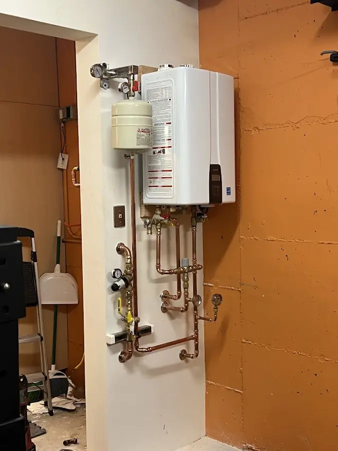 Plumbing technician inspecting water heater connections in Monson